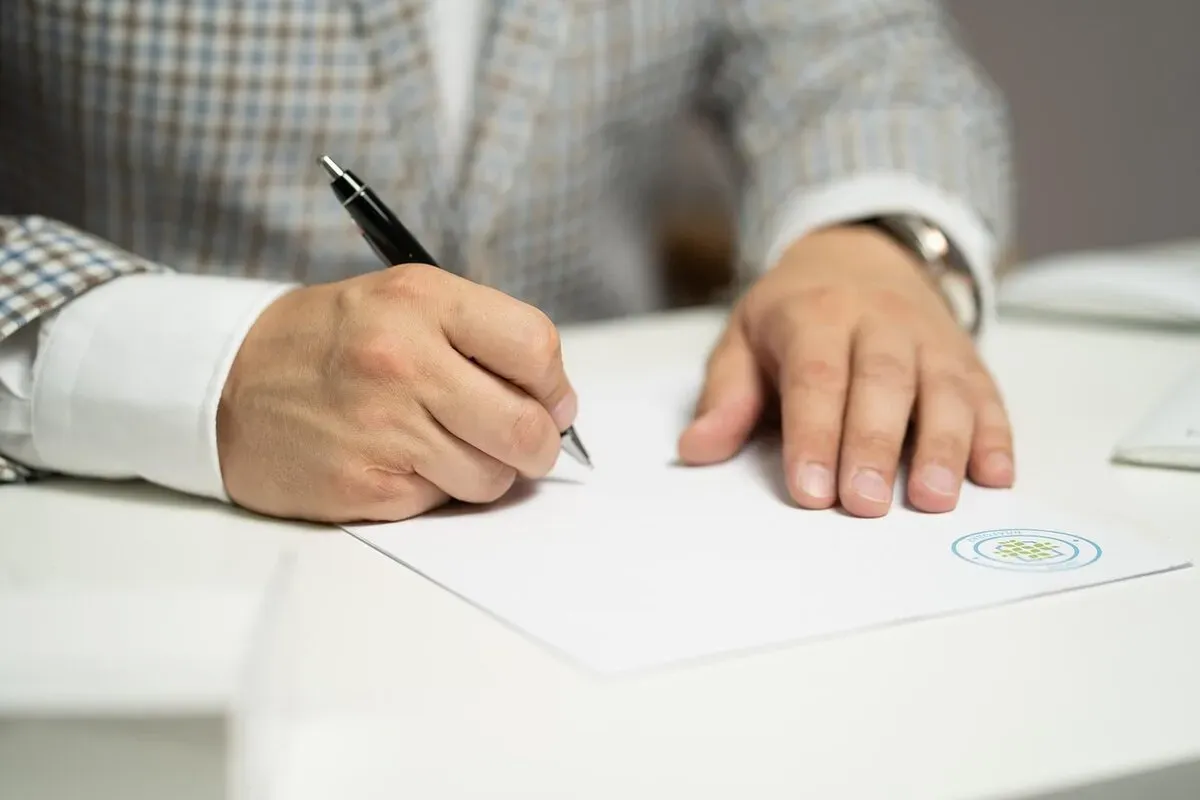 Mains d'une personne remplissant des documents administratifs pour l'accompagnement des familles.