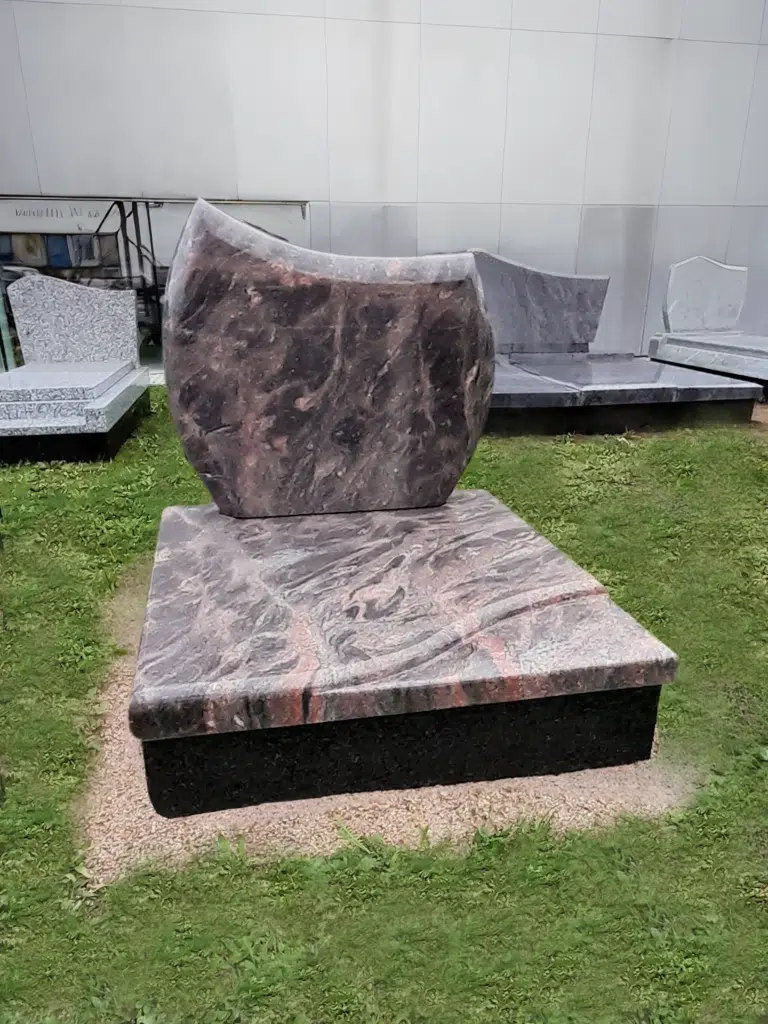 Monument cinéraire moderne en granit marbré rose et noir.