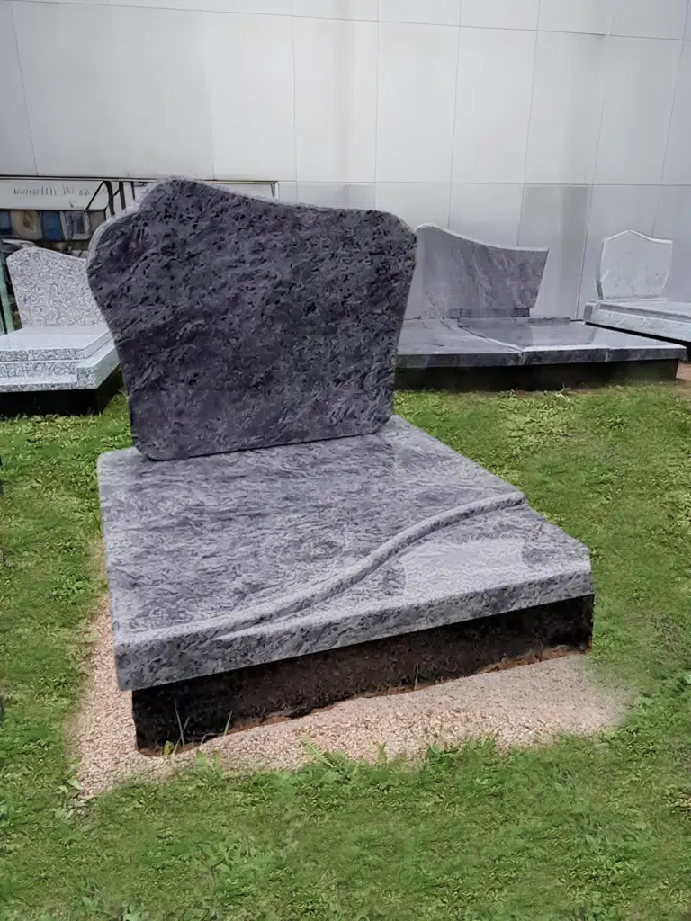 Monument cinéraire sobre en granit bleu nuit texturé.