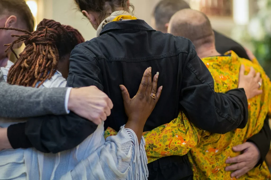 Groupe de personnes de dos s'étreignant en signe de soutien et de solidarité.