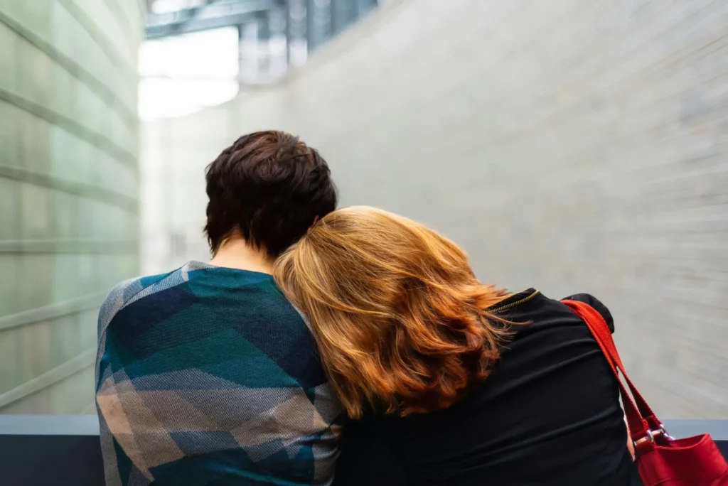 Deux personnes de dos s'étreignant, une tête reposant sur l'épaule de l'autre.